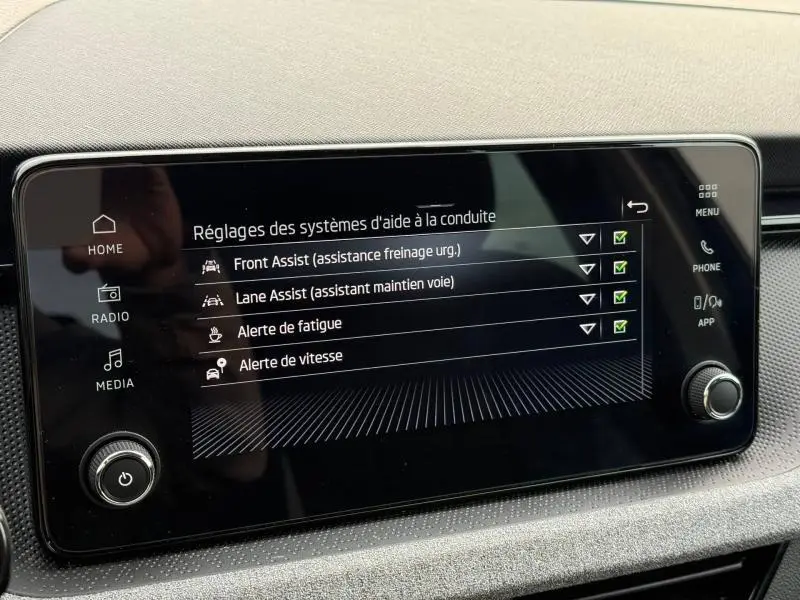 Écran tactile central du Skoda Kamiq 2024 affichant les réglages des aides à la conduite, intérieur sobre en noir.