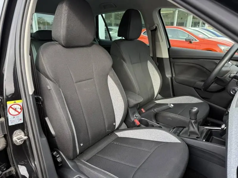 Vue intérieure côté conducteur du Skoda Kamiq 2024 noir Magic nacré, montrant les sièges avant et la boîte manuelle.