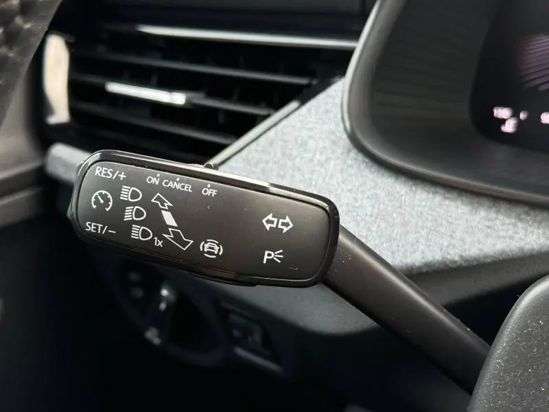 Gros plan sur la commande de régulateur de vitesse et clignotants à gauche du volant d’un Skoda Kamiq noir Magic nacré 2024.