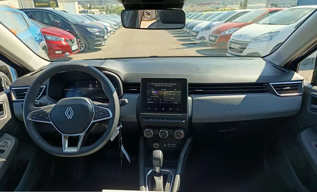 Vue intérieure frontale du tableau de bord de la Renault Clio 2025 avec écran tactile central et volant multifonctions.