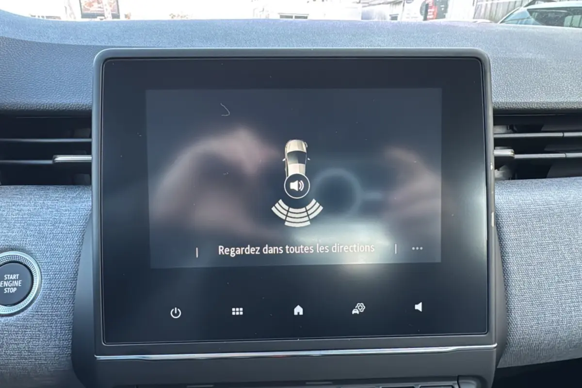 Écran tactile central de la Renault Clio gris schiste affichant une alerte de détection d'obstacles avec bouton Start/Stop visible.
