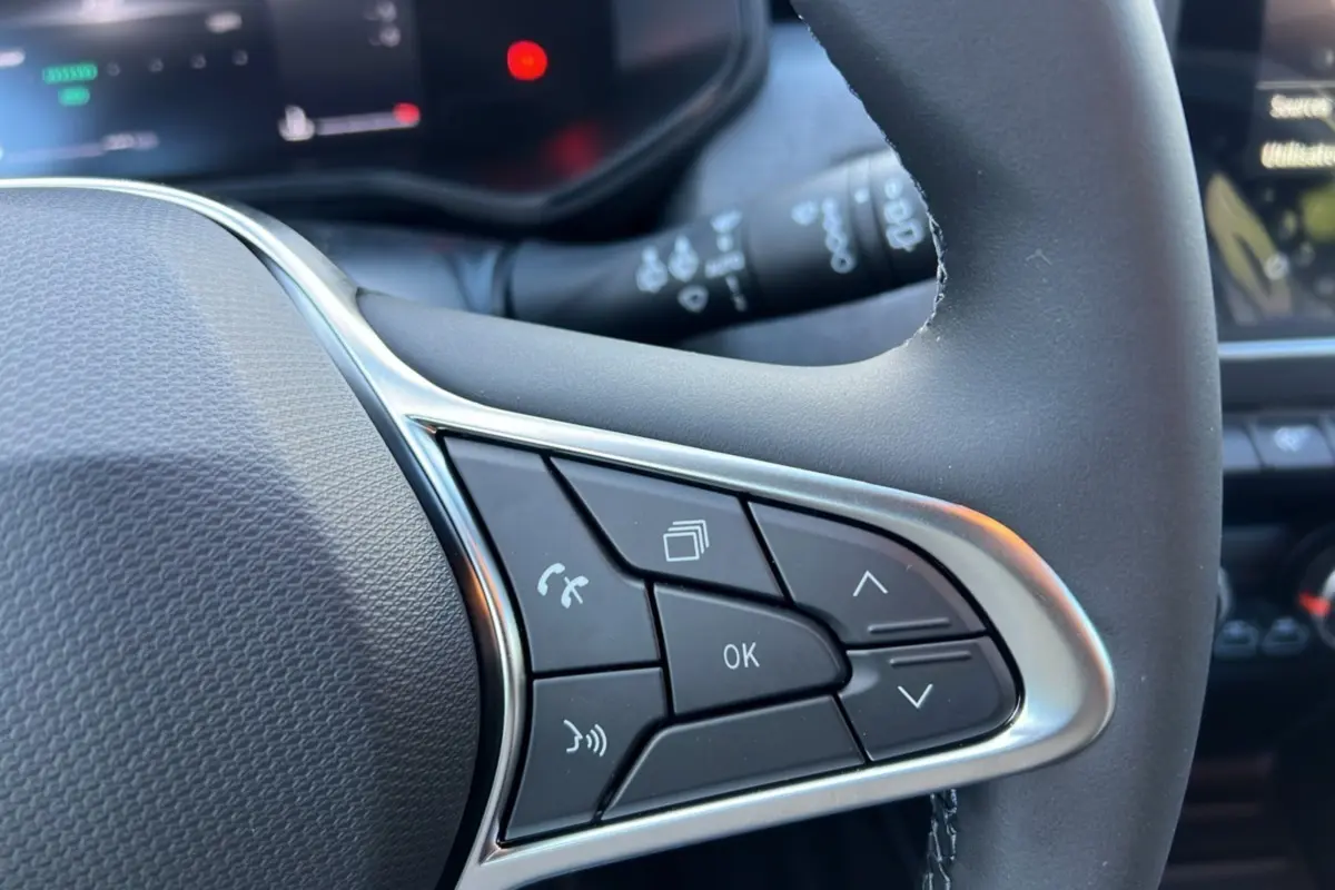 Gros plan sur les commandes multifonctions noires avec contour argenté du volant d’une Renault Clio gris schiste 2025.