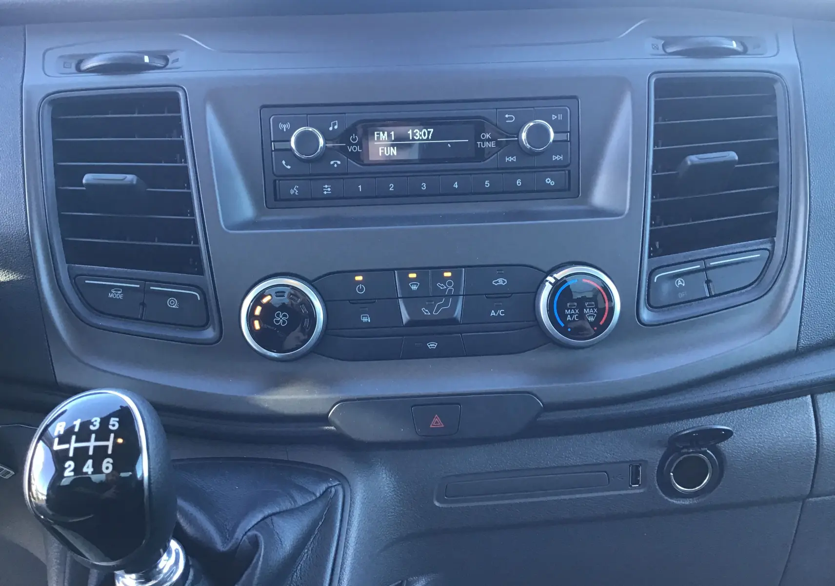 Tableau de bord du Ford Transit Chassis Cabine blanc 2024, vue frontale centrée sur la console et levier de vitesses manuel.