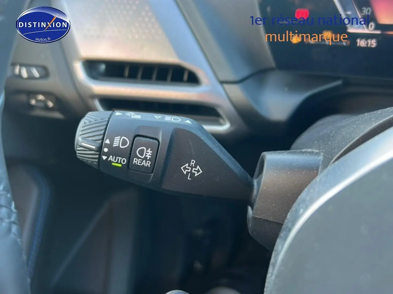 Gros plan sur la commande des phares et clignotants à gauche du volant dans une BMW Série 1 blanche alpine 2025.