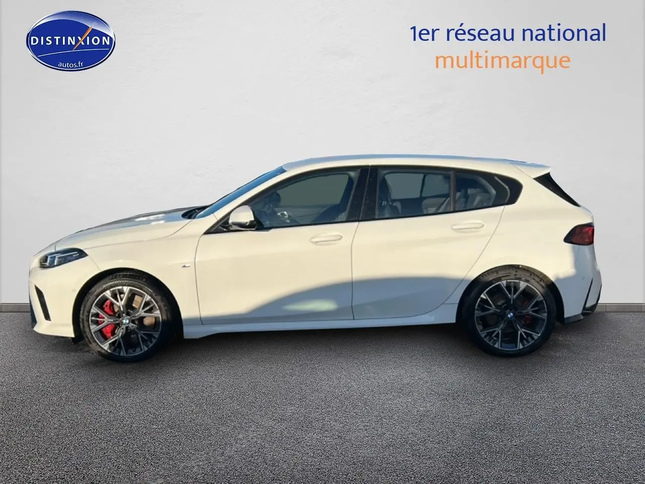BMW Série 1 118da 2025 blanc alpin vue de profil côté gauche avec jantes 18 pouces bicolores et étriers rouges.