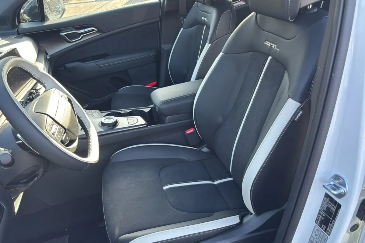 Intérieur avant droit du KIA SPORTAGE 2026 blanc nacré, sièges sport GT Line noirs avec surpiqûres blanches et volant cuir multifonctions.