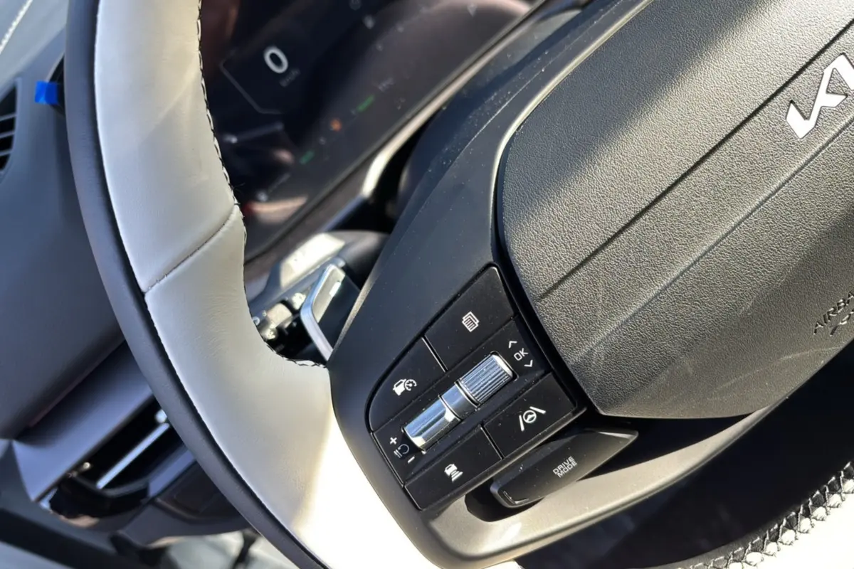 Gros plan sur le volant cuir beige clair du Kia Sportage 2026 avec commandes multifonctions et palettes au volant.