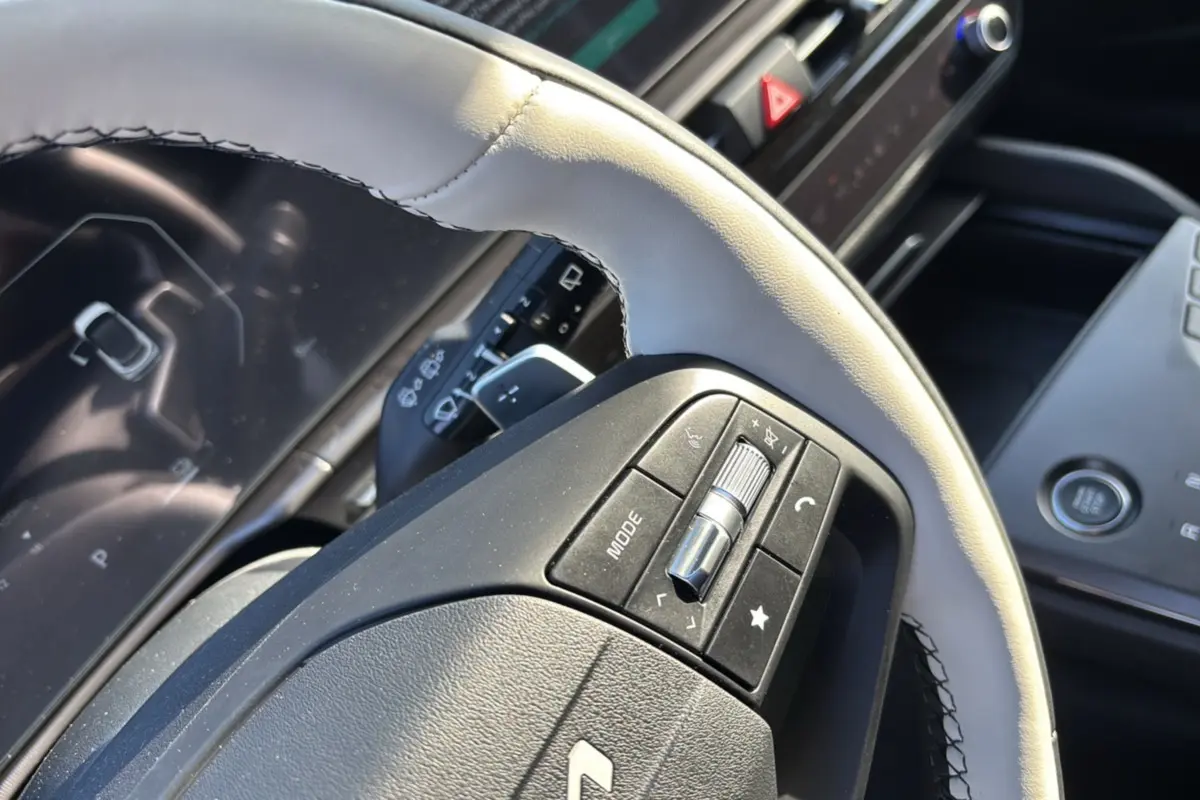 Gros plan sur le volant cuir clair du KIA SPORTAGE 2026, avec commandes multifonctions et tableau de bord numérique en arrière-plan.