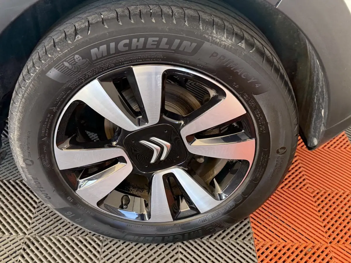 Gros plan sur la roue avant droite de la Citroën C3 blanche, avec jante alliage bicolore et logo Citroën central.