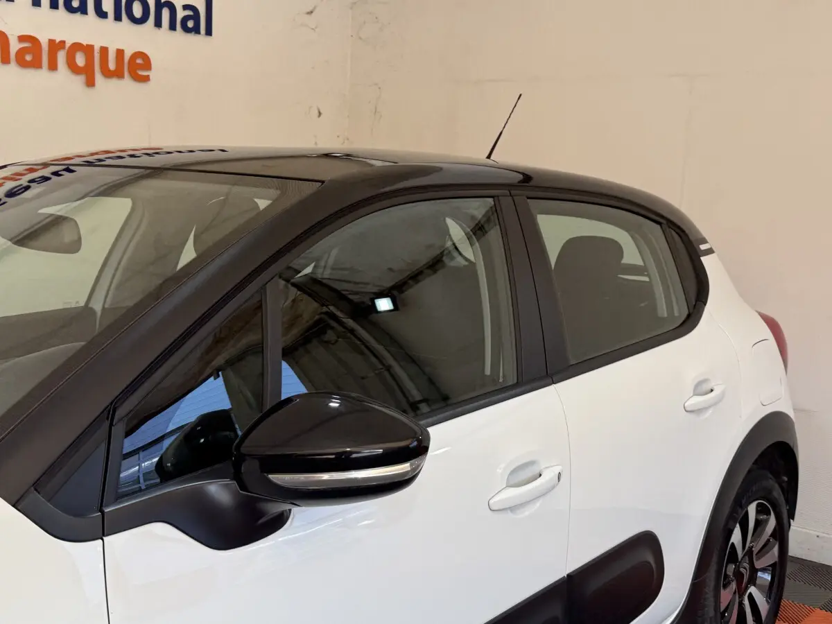 Vue côté droit arrière d'une Citroën C3 blanche avec toit noir et rétroviseur noir brillant.