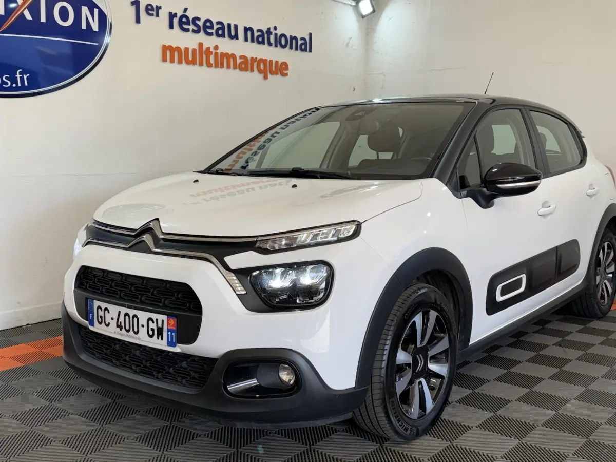 Citroën C3 blanche vue 3/4 avant droit, avec protections latérales noires et jantes alliage distinctives.
