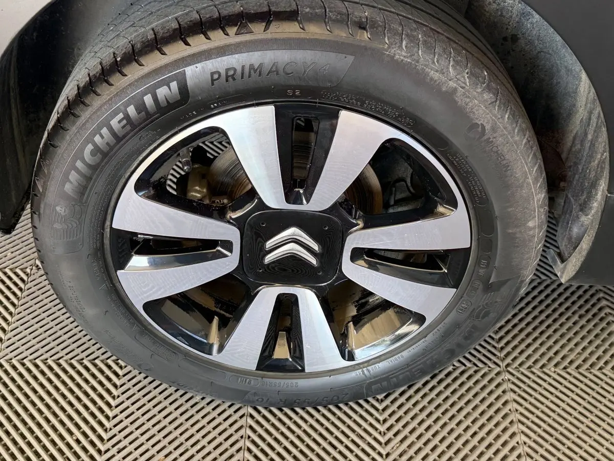 Gros plan sur la roue avant droite d'une Citroën C3 blanche, jante alliage bicolore avec logo Citroën central.