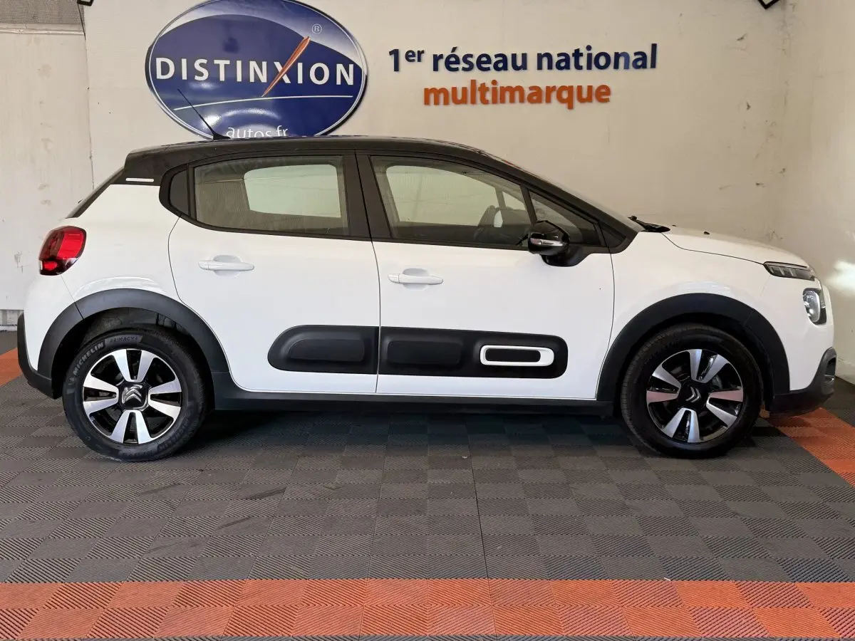 Profil droit d'une Citroën C3 blanche 2021 avec protections latérales noires et jantes distinctives bicolores.