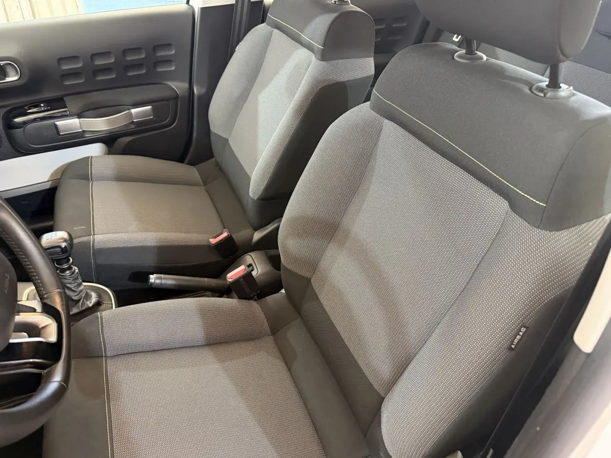 Vue intérieure rapprochée des sièges avant gris et noir de la Citroën C3 2021 avec levier de vitesse manuel visible.