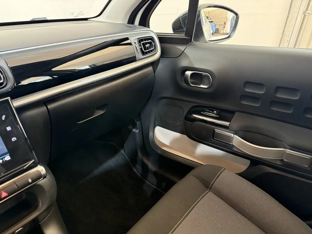 Vue intérieure côté passager de la Citroën C3 blanche 2021, avec tableau de bord noir brillant et porte au design original.