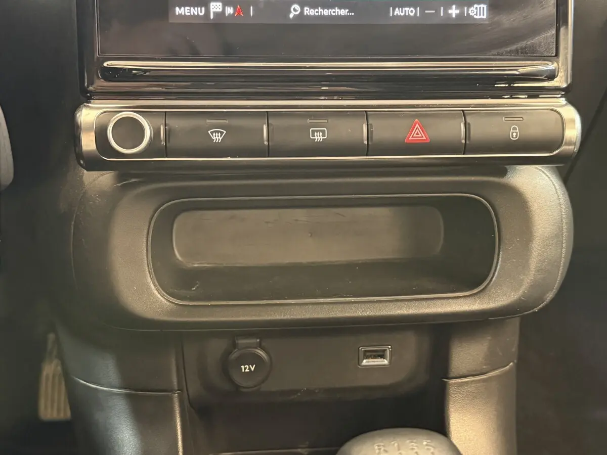 Détail du tableau de bord noir de la Citroën C3 2021, avec boutons de contrôle et prise 12V visible.