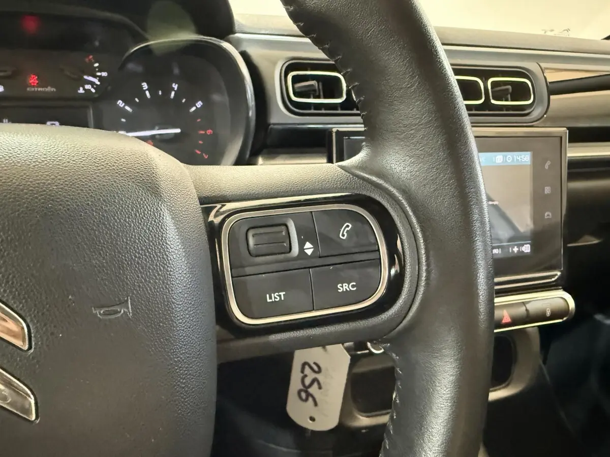 Gros plan sur le volant cuir noir de la Citroën C3 2021 avec commandes audio et écran tactile central en arrière-plan.