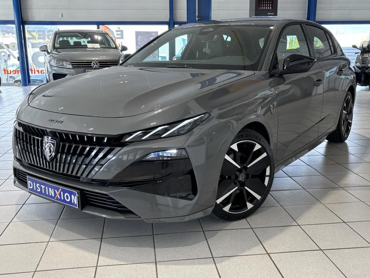 Peugeot 308 gris selenium vue 3/4 avant droit avec calandre noire brillante et jantes alliage bi-ton.