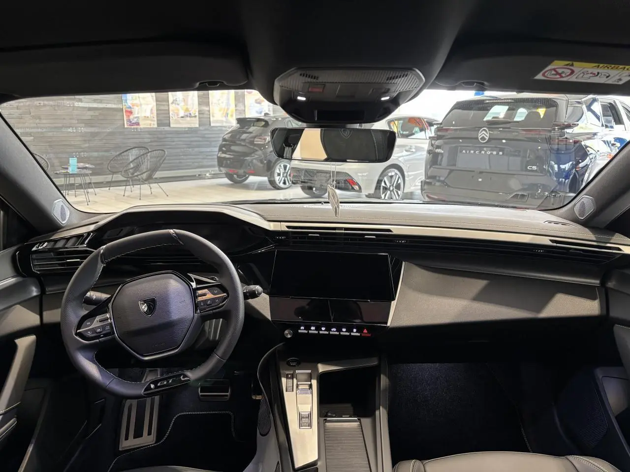 Vue intérieure avant de la Peugeot 308 gris selenium, volant compact GT et écran tactile central noir brillant.