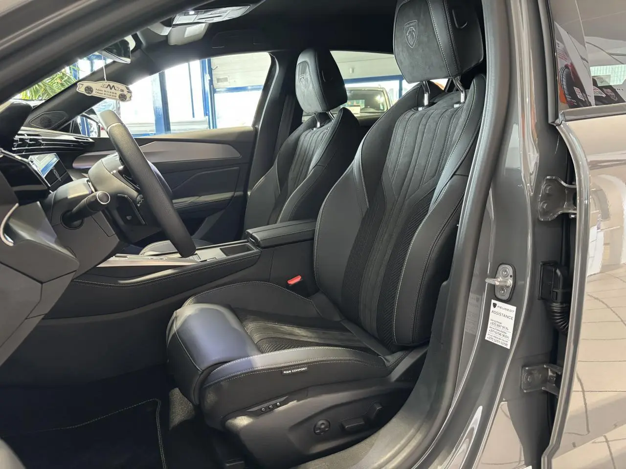 Vue intérieure côté conducteur de la Peugeot 308 gris selenium, sièges Alcantara noirs avec surpiqûres vert Adamite.