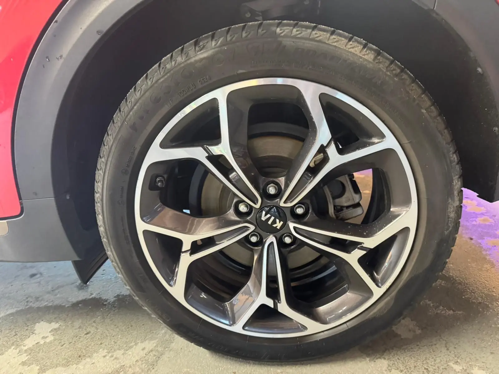 Gros plan sur la roue avant droite du Kia Sportage rouge 2019, mettant en valeur la jante alliage au design moderne.