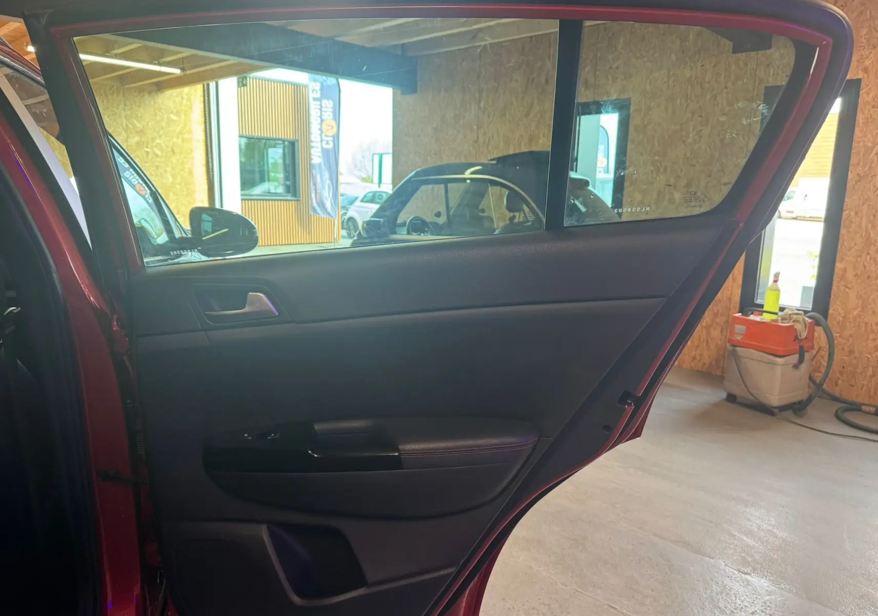 Vue intérieure de la porte arrière gauche rouge du KIA SPORTAGE 1.6 CRDI 136 GT LINE, avec garniture noire et poignée intégrée.