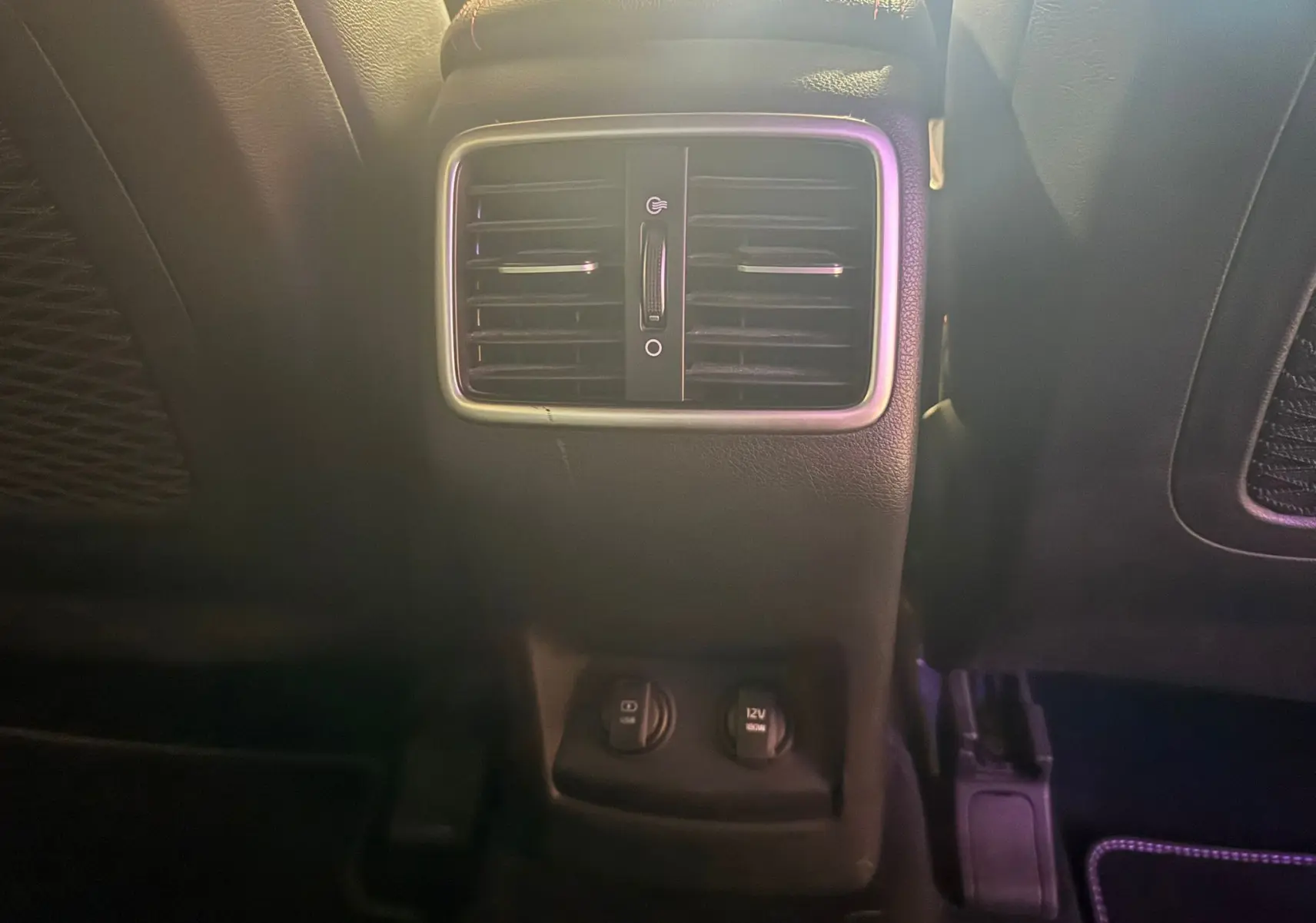 Vue rapprochée des aérateurs arrière et prises 12V du siège arrière d’un KIA Sportage rouge 2019, intérieur noir.