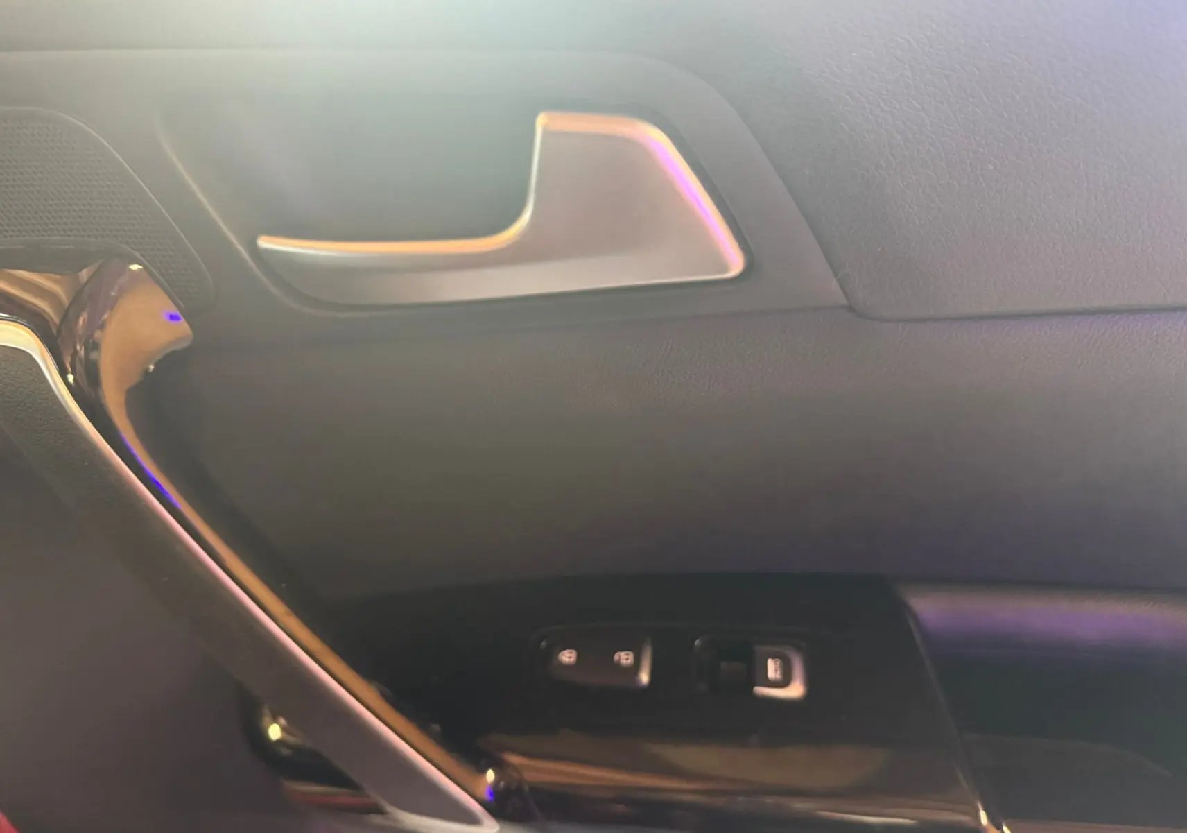 Détail de la porte intérieure côté gauche d’un KIA Sportage rouge 2019, avec poignée argentée et commandes de vitres.