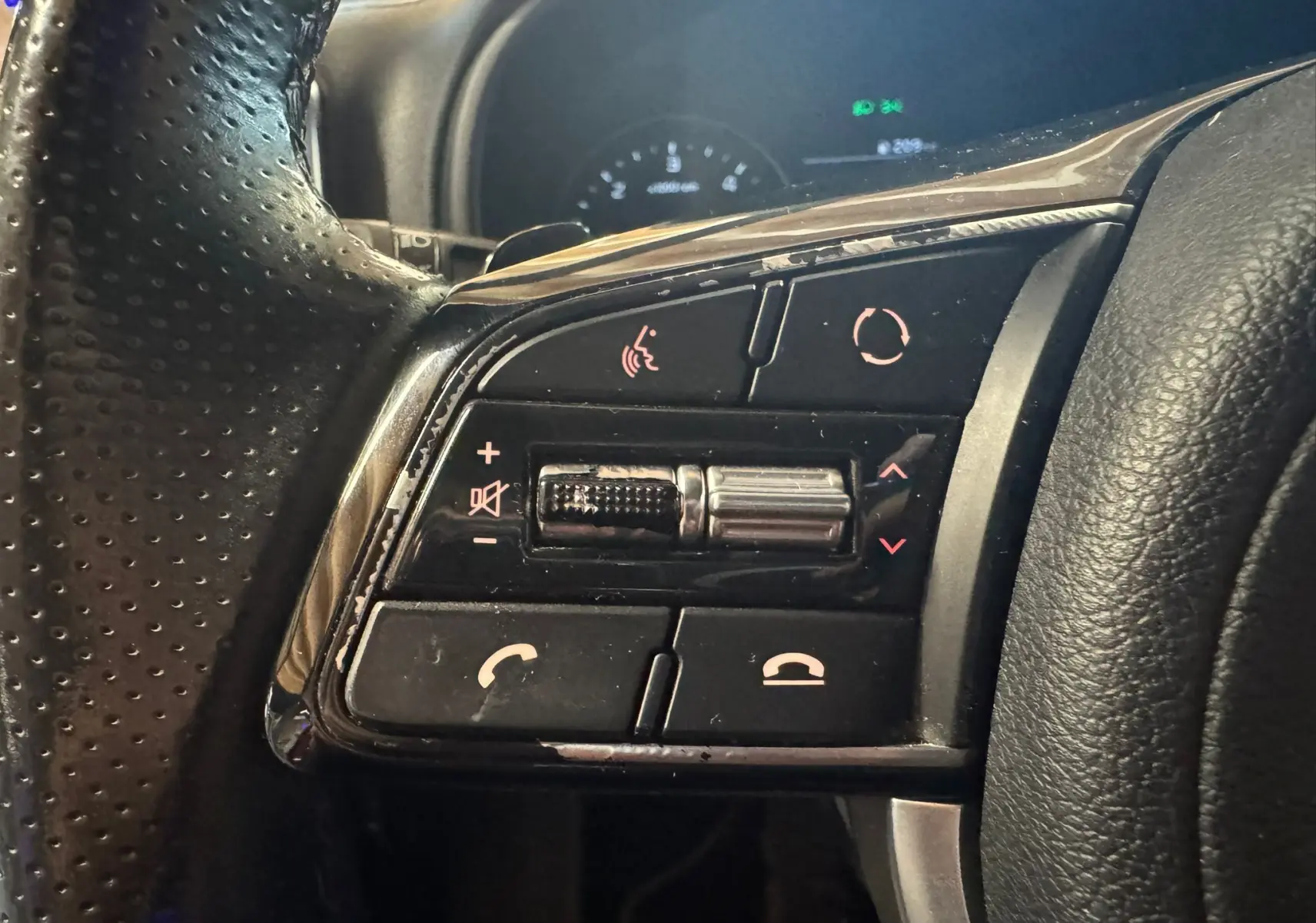 Gros plan sur les commandes multifonctions côté gauche du volant en cuir noir du Kia Sportage rouge, version GT Line 2019.