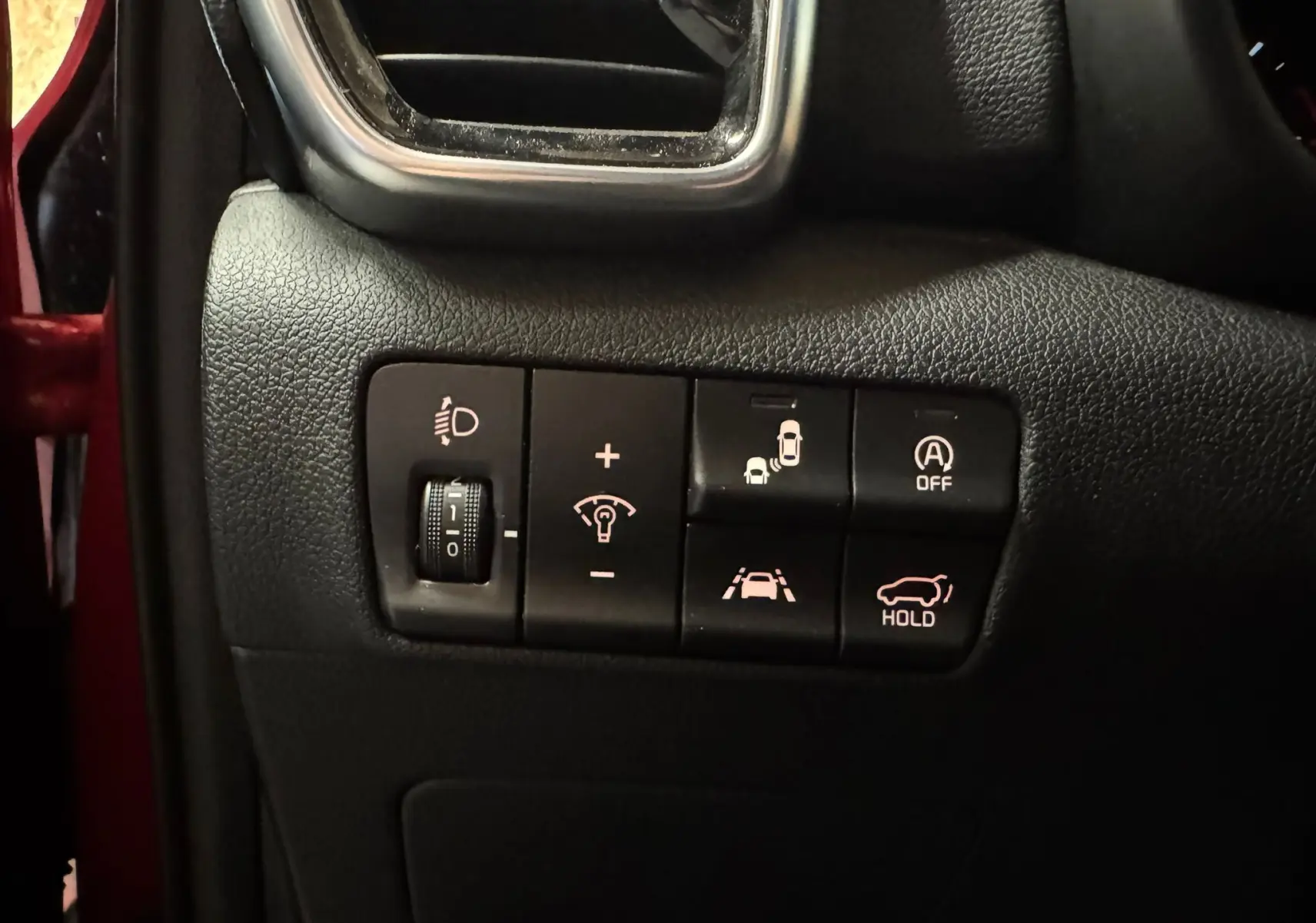 Gros plan sur les commandes de sécurité et assistance du tableau de bord d’un KIA Sportage rouge, version 2019.