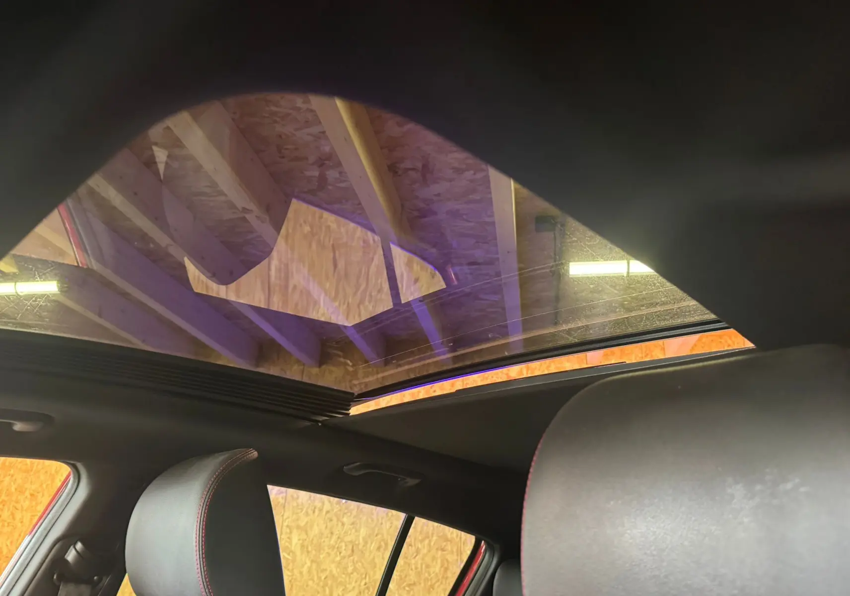 Vue intérieure du toit ouvrant panoramique du Kia Sportage rouge 2019, avec sièges en cuir noir visibles.