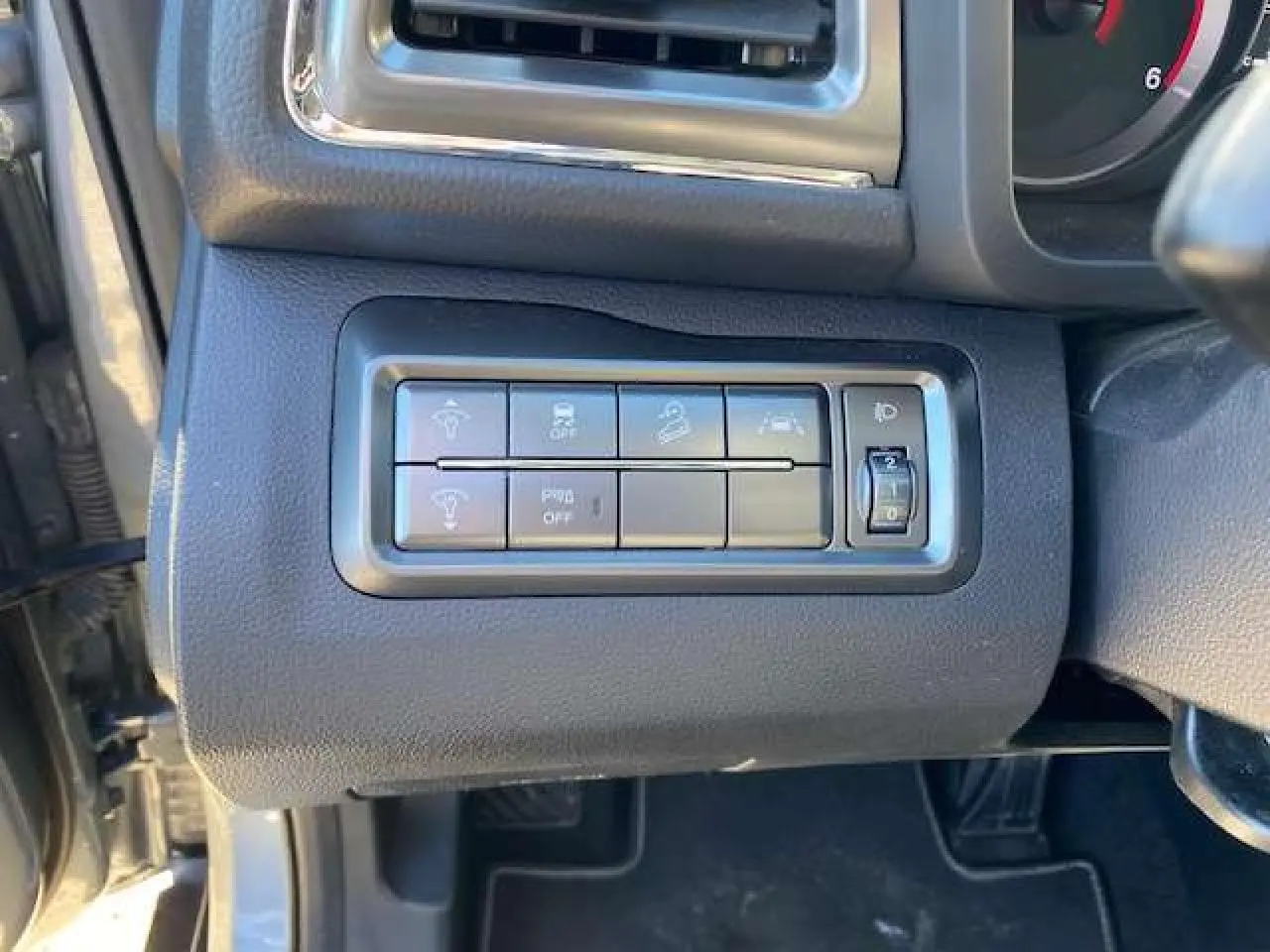 Gros plan sur les commandes d'assistance et réglage des phares du SSANGYONG TIVOLI gris foncé, côté conducteur.
