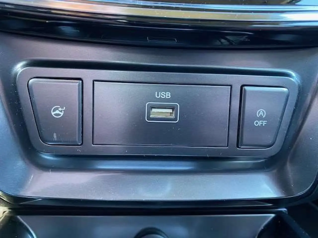 Gros plan sur la prise USB et boutons de commande noirs dans l'habitacle du SsangYong Tivoli gris foncé.