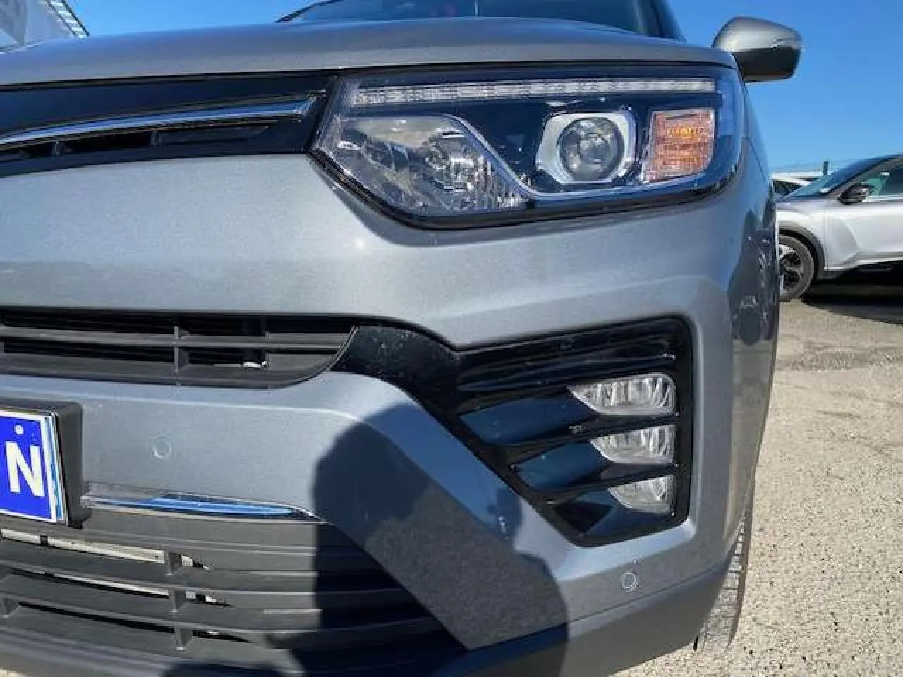 Gros plan sur l’avant droit gris foncé du SsangYong Tivoli 2021, mettant en valeur ses phares LED et la calandre noire.