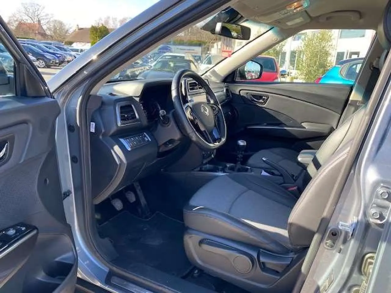 Vue intérieure côté conducteur du SsangYong Tivoli gris foncé 2021, volant cuir et tableau de bord moderne.