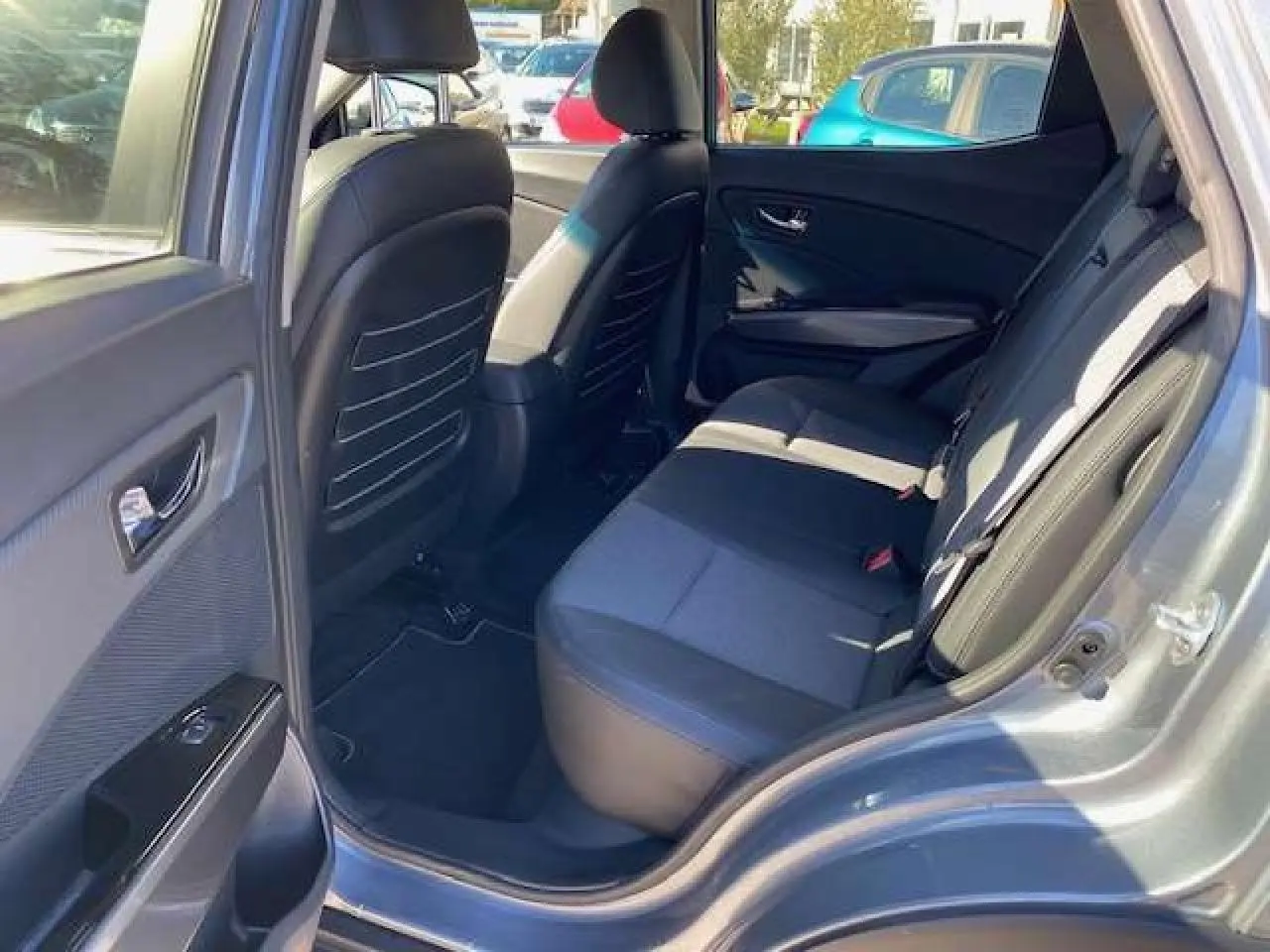 Vue côté gauche arrière du SSANGYONG TIVOLI gris foncé montrant l'intérieur des sièges arrière et la portière ouverte.