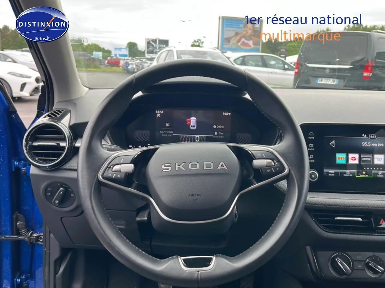 Vue intérieure centrée sur le volant cuir noir de la Skoda Fabia bleu 2025 avec tableau de bord digital et écran tactile.
