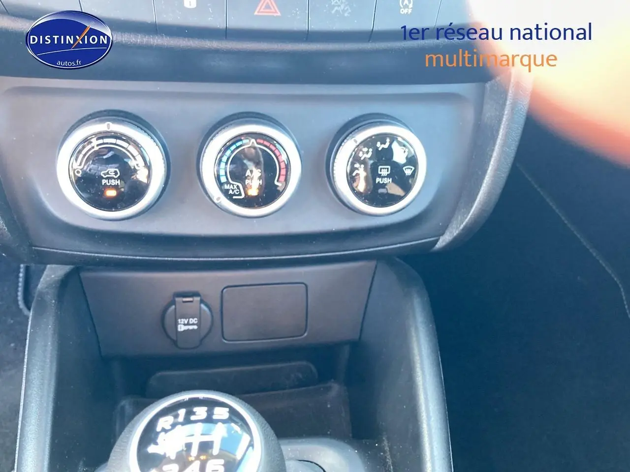 Gros plan sur la console centrale du Fiat Tipo bleu 2024, mettant en valeur les commandes de climatisation et le levier de vitesse manuel.