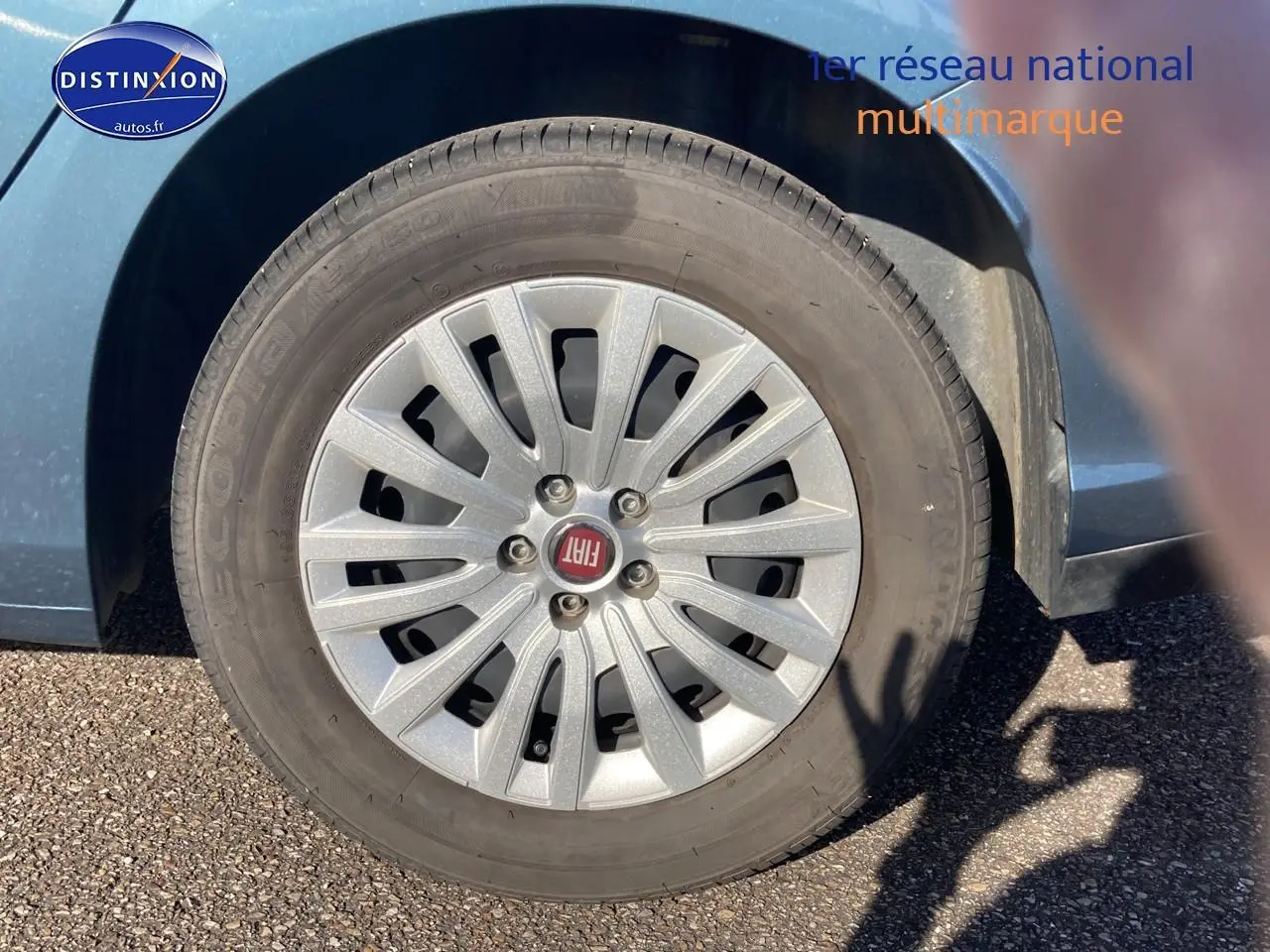 Gros plan sur la roue avant gauche d'une Fiat Tipo bleu avec enjoliveur argenté et logo FIAT au centre.