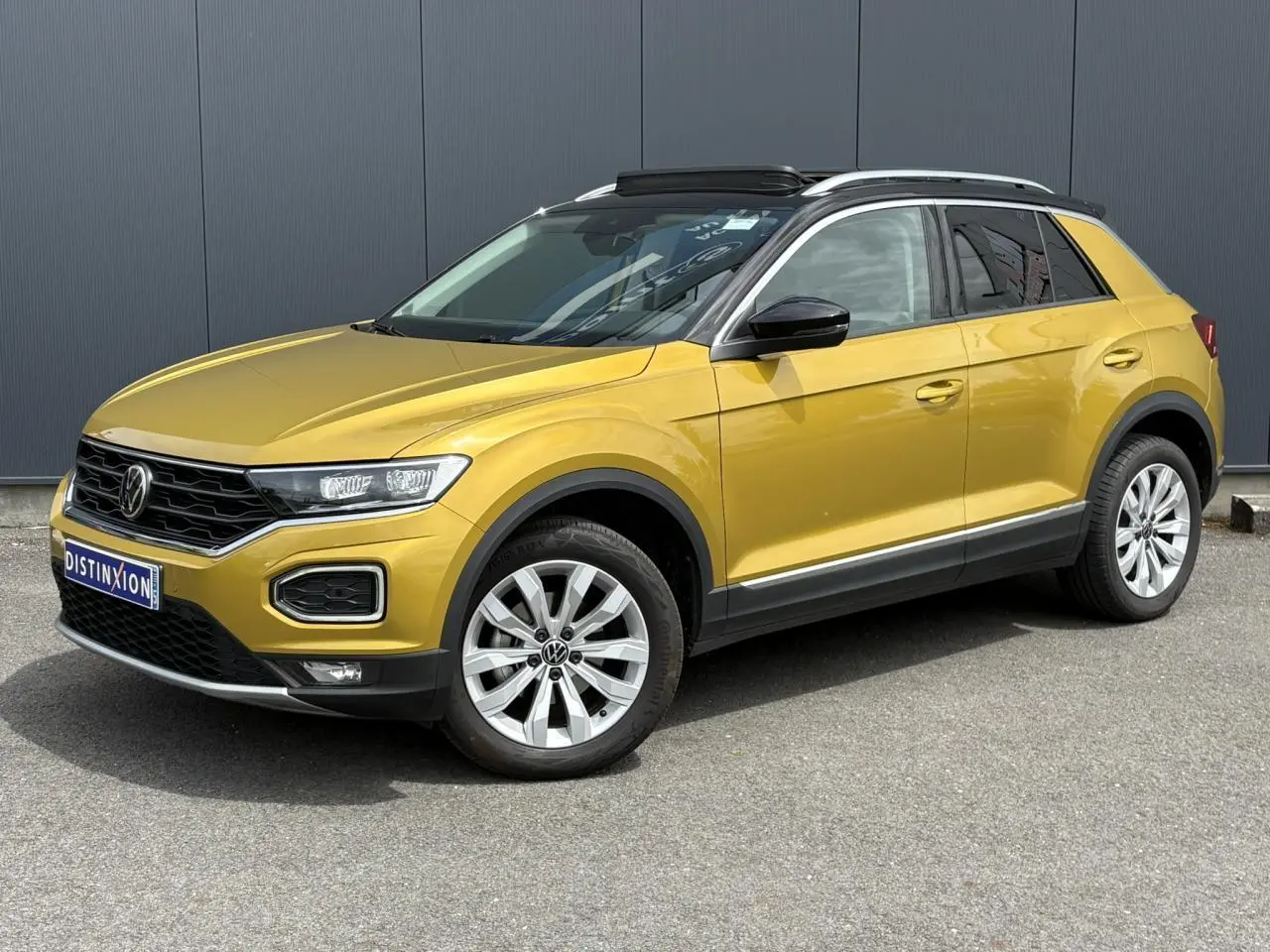 Volkswagen T-Roc jaune curcuma vue 3/4 avant droit avec toit ouvrant noir et jantes alliage 17 pouces.