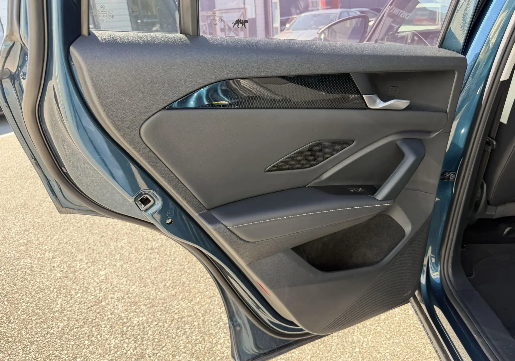 Vue rapprochée de la porte arrière gauche ouverte du Volkswagen Tiguan 2025 bleu, montrant les finitions intérieures en noir et chrome.