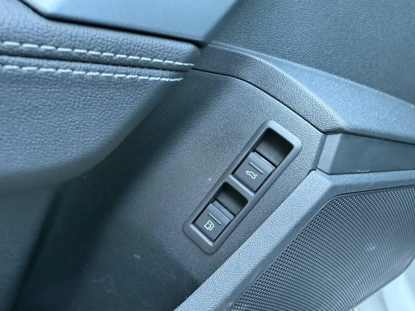 Détail des commandes d'ouverture de coffre et de trappe à carburant sur la porte côté conducteur d'Audi A3 Sportback blanc Glacier.