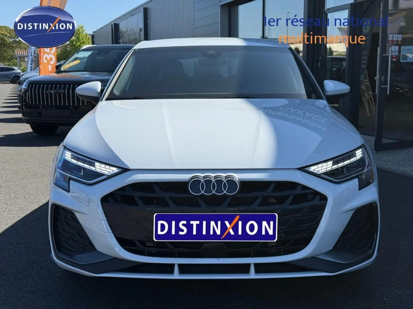 Vue frontale d'une Audi A3 Sportback blanche Glacier métallisé avec calandre noire et phares LED distinctifs.