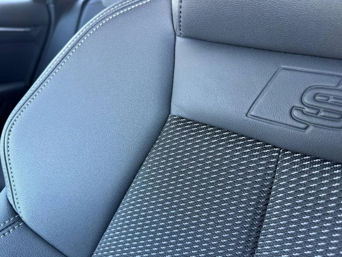Gros plan sur le siège avant en tissu noir et simili avec logo S line embossé, intérieur Audi A3 Sportback 2025.