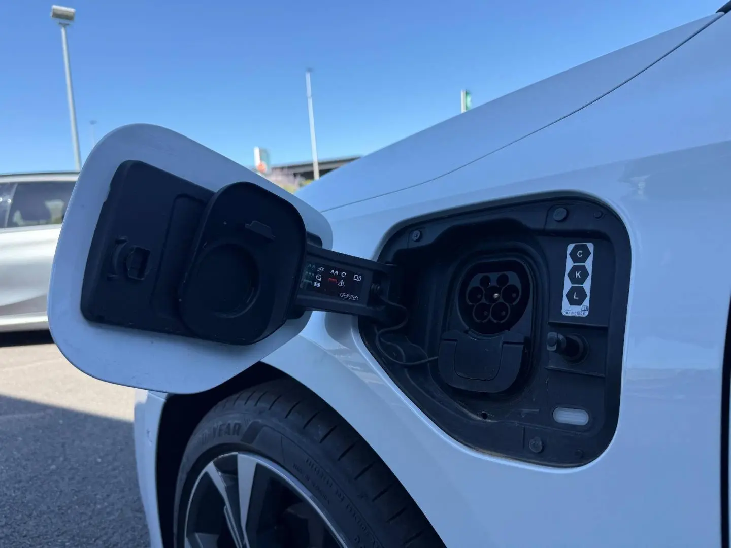 Prise de recharge ouverte côté gauche arrière d’Audi A3 Sportback blanc Glacier métallisé, jante alu visible.