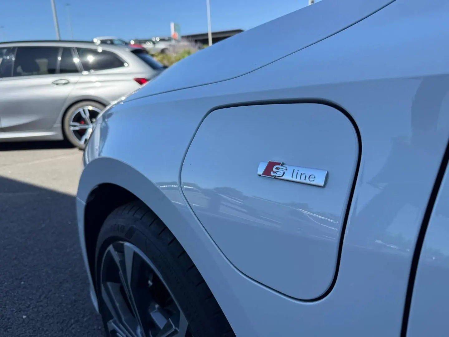 Gros plan sur la trappe de recharge côté avant gauche d’une Audi A3 Sportback blanc Glacier métallisé avec logo S line.
