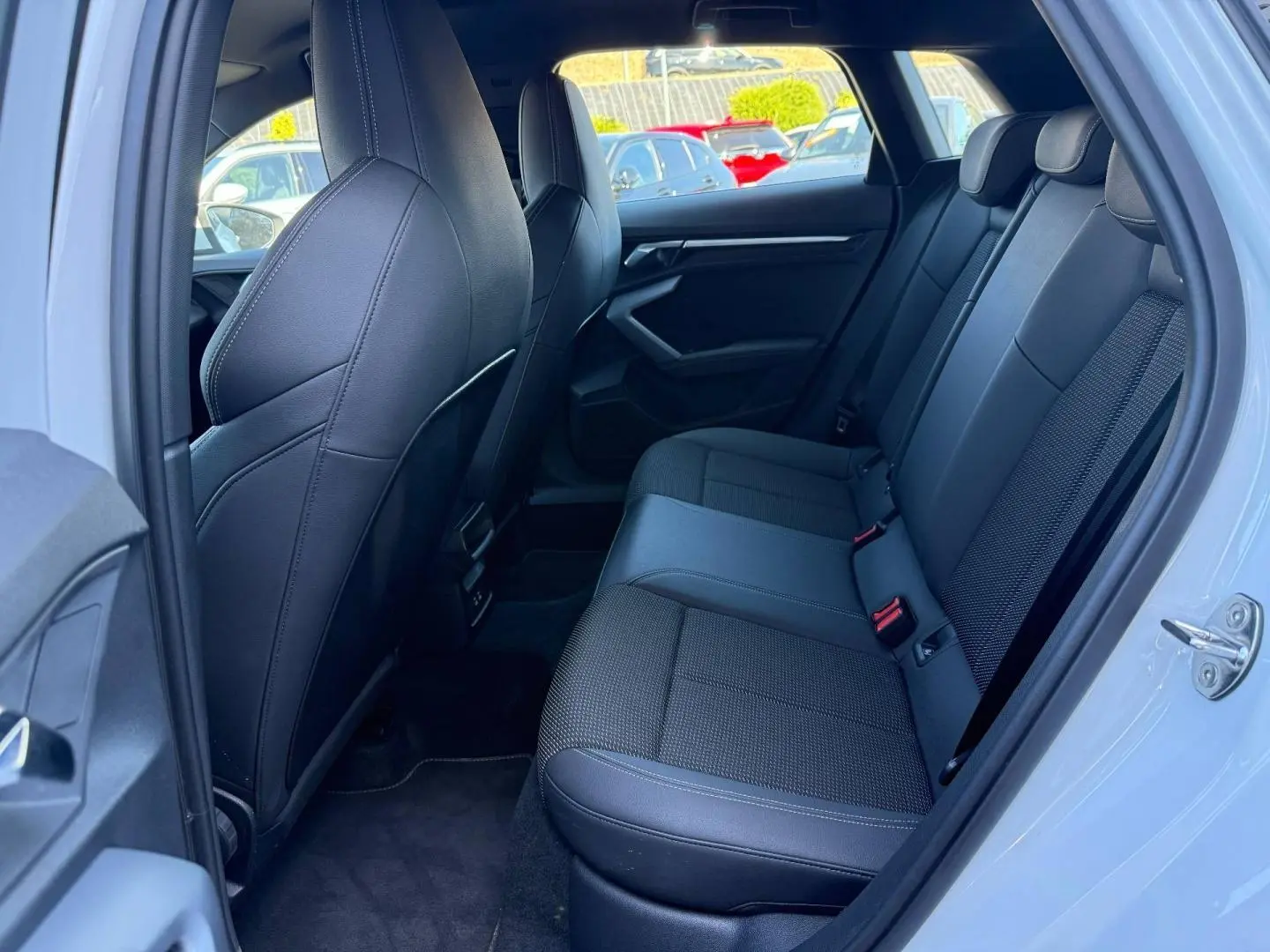 Vue intérieure côté droit sur la banquette arrière noire en tissu et simili de l’Audi A3 Sportback Blanc Glacier.