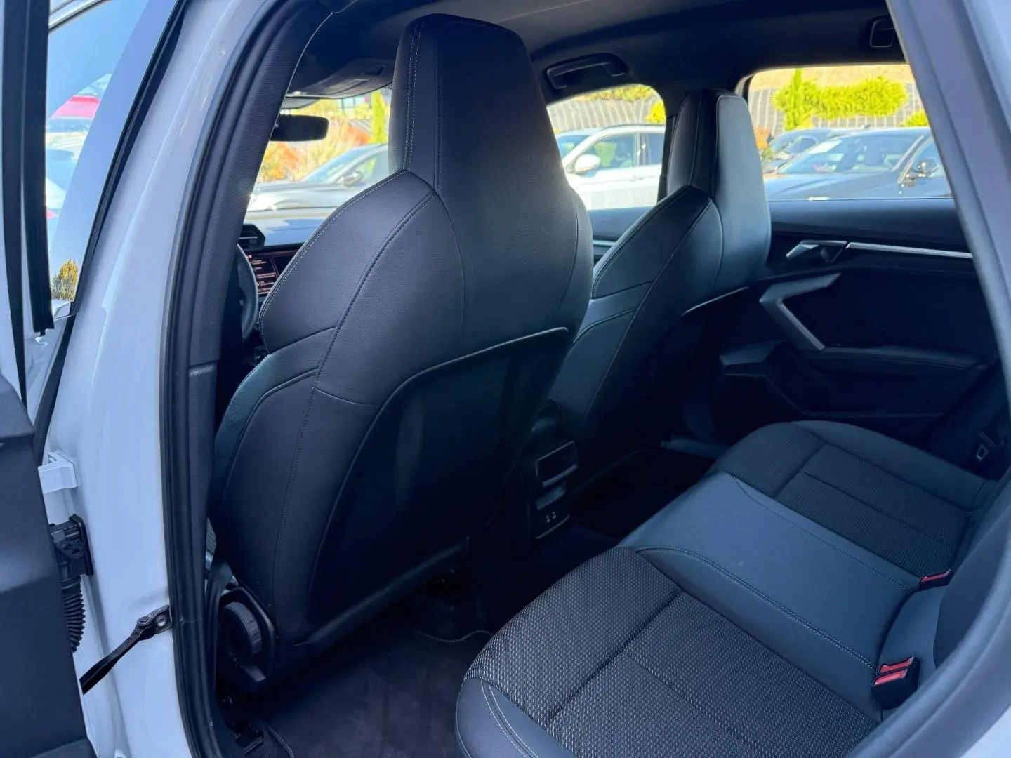 Vue intérieure arrière côté gauche d’une Audi A3 Sportback blanche avec sièges sport noirs et finitions modernes.