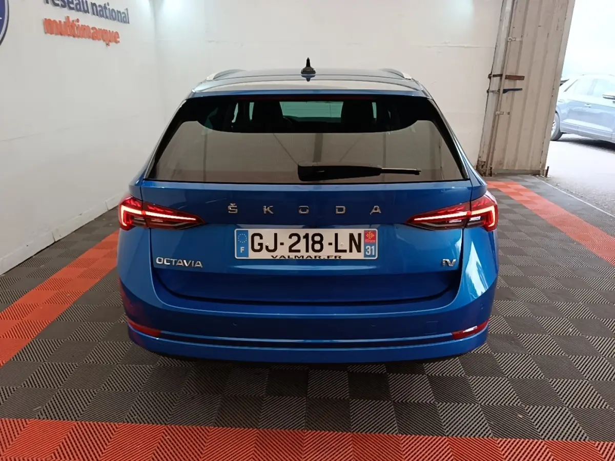 Vue arrière d'une Skoda Octavia bleu électrique avec feux LED allumés dans un garage.