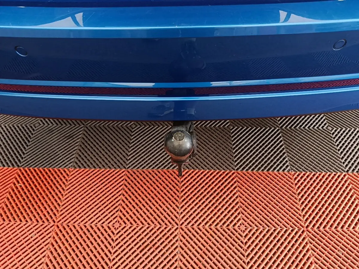 Gros plan sur l'attelage arrière d'une Skoda Octavia bleu, avec pare-chocs et capteurs de stationnement visibles.